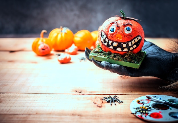 Feliz Dia das Bruxas. Mãos de lobisomem ou zumbis pintando uma abóbora assustadora para uma festa de doces ou travessuras. copie o espaço para o texto