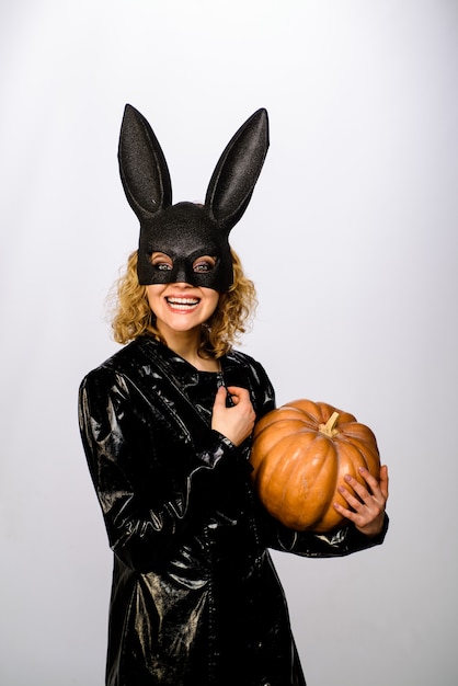 Feliz dia das bruxas modelo feminino sexy com máscara de coelho preto de coelhinho da Páscoa com menina bonita jackolantern