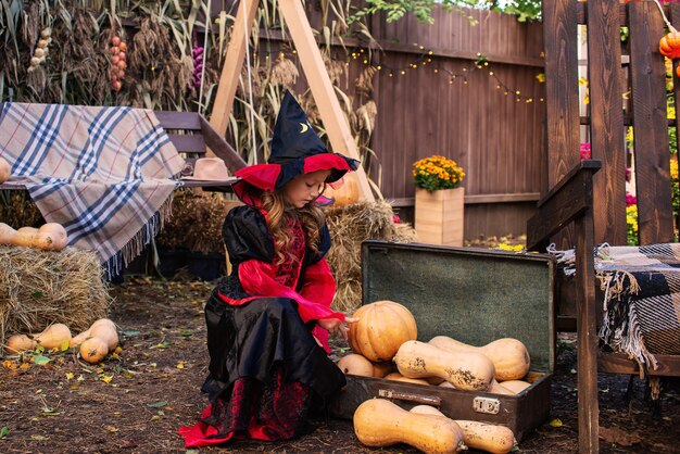 feliz dia das bruxas uma garota fantasiada de bruxa com uma abóbora se divertindo no outono perto de casa
