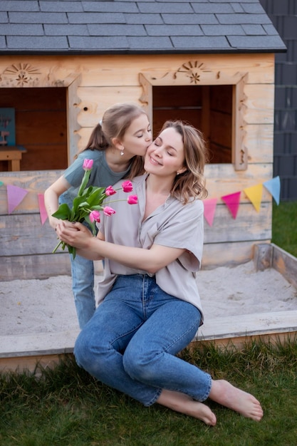 Feliz dia das mães A filha criança está parabenizando a mãe e dando flores tulipas Mãe e menina sorrindo e abraçando Férias em família e união