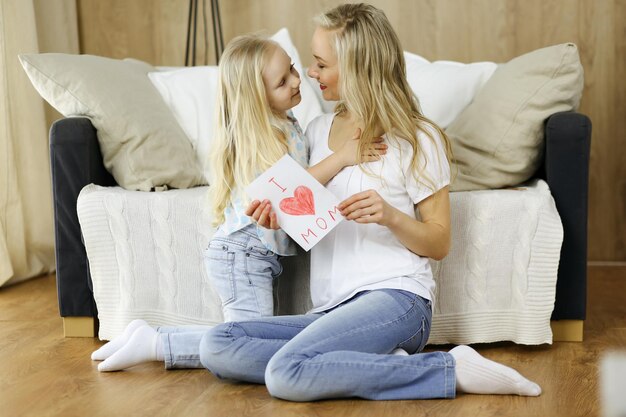 Feliz dia das mães. A filha felicita a mãe e dá-lhe um cartão postal com um desenho de coração. Conceitos de família e infância.