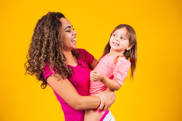 Feliz Dia das Mães! Adorável criança caucasiana com sua mãe em fundo amarelo.