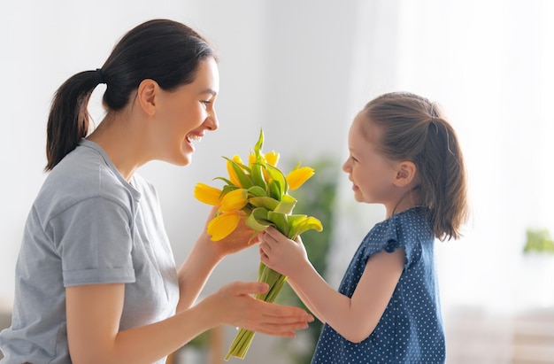 Feliz dia das mães Filha criança felicita a mãe e dá-lhe flores