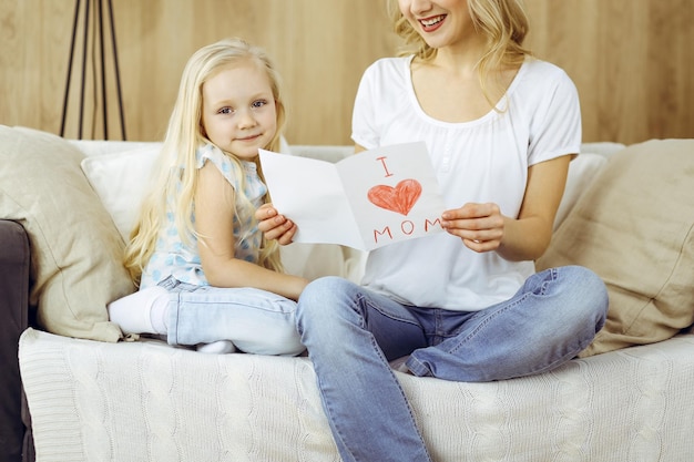 Feliz dia das mães! filha criança felicita a mãe e dá seu cartão postal com desenho de coração. conceitos de família e infância.