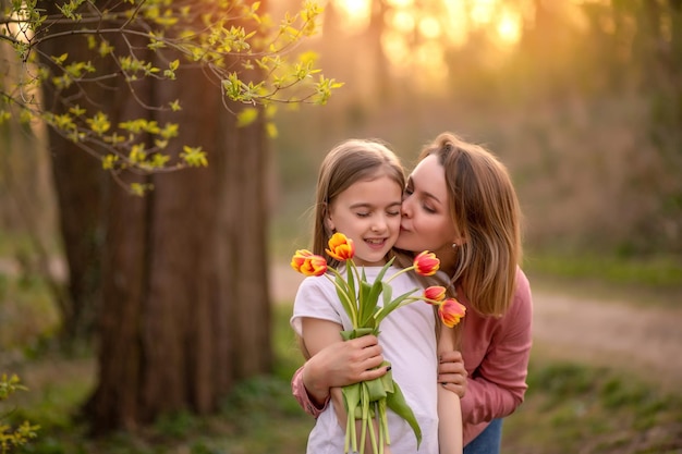 Feliz dia das mães filha criança felicita a mãe e dá um buquê de flores para tulipas