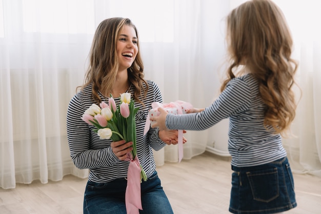 Foto feliz dia das mães. filha criança felicita mães e dá-lhe um presente e flores tulipas.