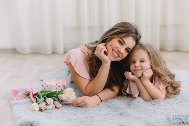 Feliz dia das mães. filha de criança felicita mãe e dá-lhe flores tulipas e presente