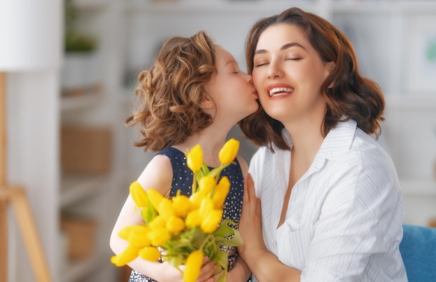 Feliz dia das mães Filha infantil parabenizando a mãe e dando-lhe flores