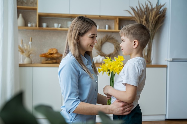 Feliz dia das mães filho dá flores para a mãe flores nas mãos de um menino 8 de março