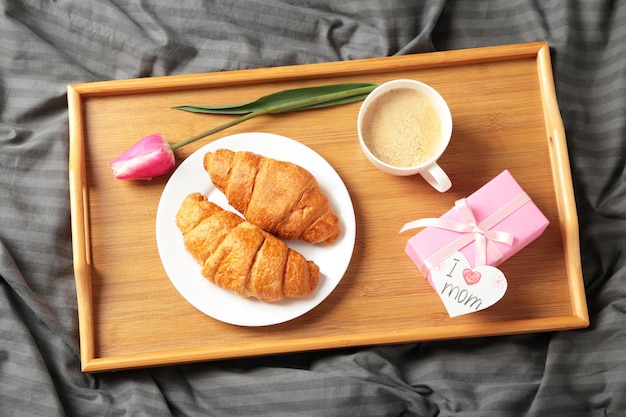 Feliz dia das mães lindo café da manhã na bandeja almoço com xícara de café croissants frescos tulipa e presente férias de primavera relações familiares