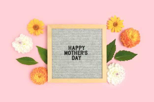 Feliz Dia das Mães Quadro de cartas com moldura feita de flores dálias e folhas verdes em um fundo rosa Layout festivo