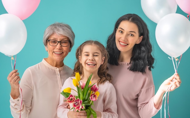 Feliz dia das mulheres A filha criança está parabenizando a mãe e a vovó dando-lhes tulipas de flores amarelas