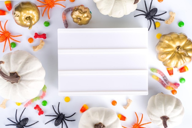 Feliz dia de Halloween fundo de férias Flat lay com doces e decorações para crianças pacote de balde de festa com aranhas doces morcego na mesa branca espaço de cópia quadro de vista superior