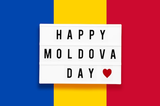 Feliz dia de moldova em uma mesa de luz em um fundo da cor da bandeira da moldávia.