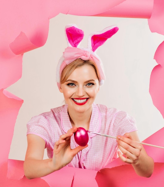 Foto feliz dia de páscoa mulher sorridente em orelhas de coelho pintando ovos de páscoa caça ao ovo conceito de dia de páscoa feliz