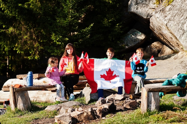 Feliz dia do Canadá. Família de mãe com três filhos segura grande celebração da bandeira canadense nas montanhas.