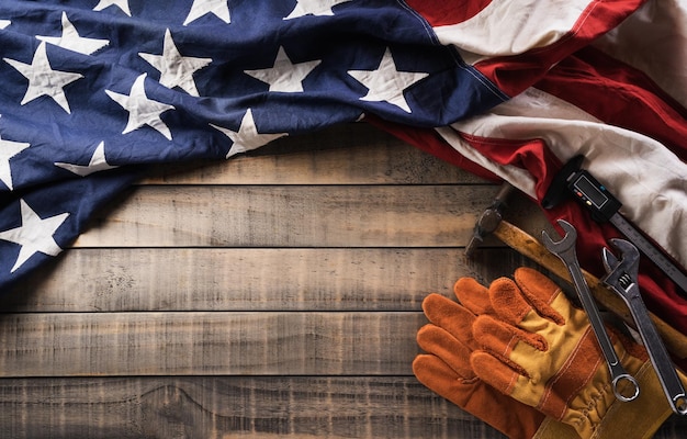 Feliz dia do trabalho bandeira americana com diferentes ferramentas de construção em fundo escuro de madeira