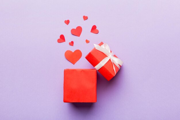 Feliz dia dos namorados caixa de presente aberta em forma de coração com pequenos corações em fundo colorido cartão de dia dos namorados conceito de vista superior