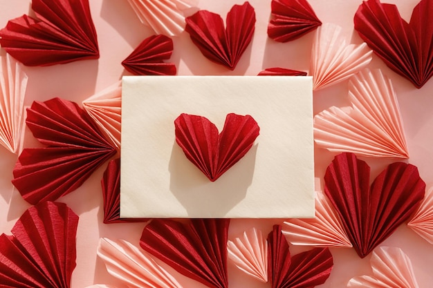 Feliz dia dos namorados Envelope elegante com corações rosa e vermelhos planos sobre fundo de papel rosa Recortes modernos de coração dos namorados Espaço para cartas de amor para texto Composição criativa