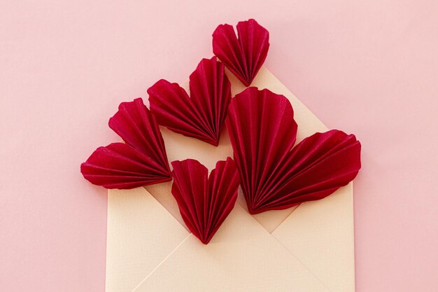 Feliz dia dos namorados Envelope estiloso com corações vermelhos em fundo de papel rosa Espaço moderno para cartão de dia dos namorados para texto Bandeira de amor Composição de carta criativa