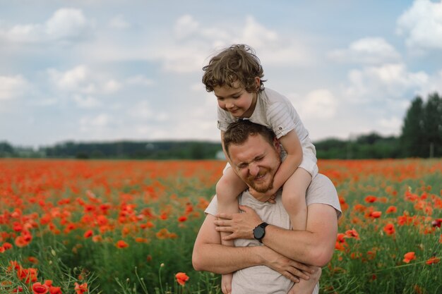 Feliz dia dos pais, filho e pai brincando em um lindo campo de papoulas vermelhas