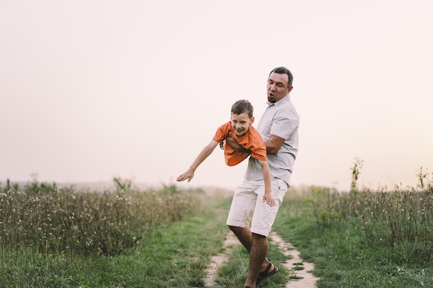 Feliz dia dos pais Pai com filho está andando no campo Pai abraça menino O conceito de relacionamento do Dia dos Pais com crianças cuida e ama