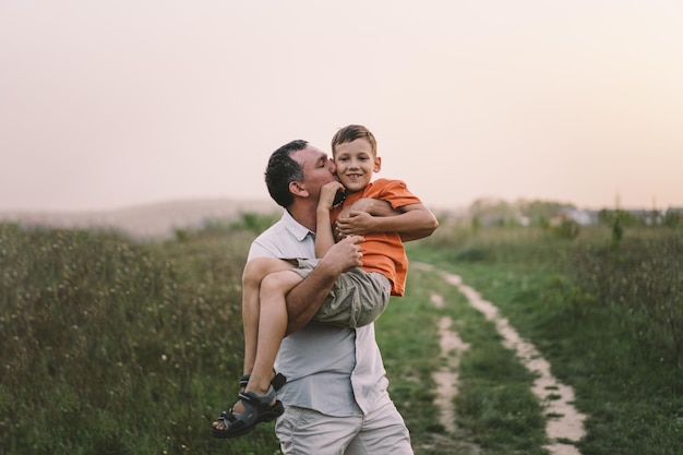 Feliz dia dos pais Pai com filho está andando no campo Pai abraça menino O conceito de relacionamento do Dia dos Pais com crianças cuida e ama