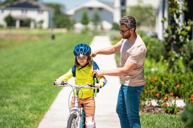 Foto feliz dia dos pais pai e filho aprendendo a andar de bicicleta se divertindo juntos no dia dos pais