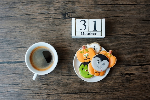 Foto feliz día de halloween con galletas, café y calendario 31 de octubre sobre fondo blanco. truco o amenaza, hola octubre, otoño otoño, concepto festivo, fiesta y vacaciones