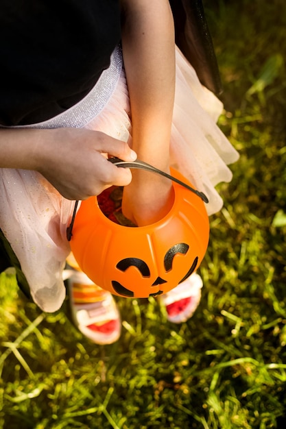 Foto feliz día de halloween un niño pequeño disfrazado de bruja está buscando dulces en su cubo de calabaza jack