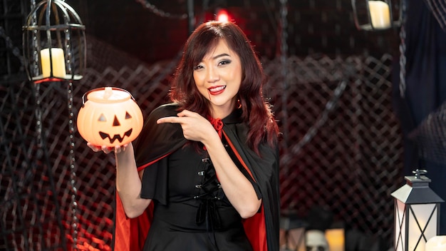 Feliz día de halloween Retrato modelo de mujer hermosa asiática vestida como una sonrisa de disfraz de bruja y sosteniendo calabaza en el tema de halloween