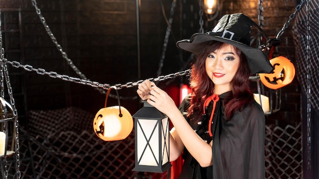 Feliz día de halloween Retrato mujer asiática en disfraz de halloween bruja sombrero negro con linterna