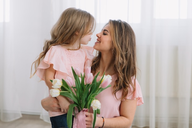 Feliz día de la madre. Hija hija felicita a las mamás y le regala flores a sus tulipanes.