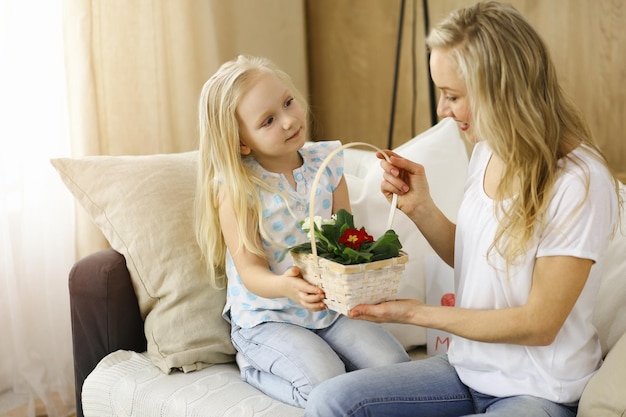 Feliz dia de LA MADRE. La hija del niño felicita a mamá y le da una canasta de flores de primavera. concepto de familia.