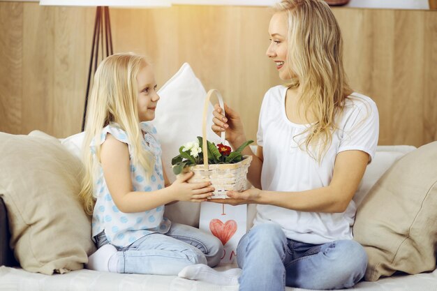 ¡Feliz dia de LA MADRE! La hija del niño felicita a mamá y le da una canasta de flores de primavera. concepto de familia.
