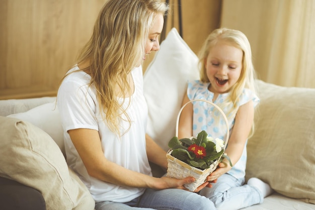 Feliz dia de LA MADRE. La hija del niño felicita a mamá y le da una canasta de flores de primavera. Conceptos de familia e infancia.