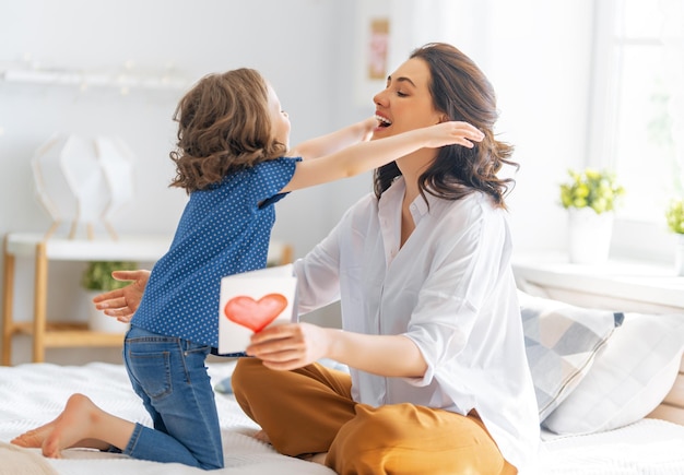 Feliz día de la madre La hija del niño felicita a mamá y le da una postal