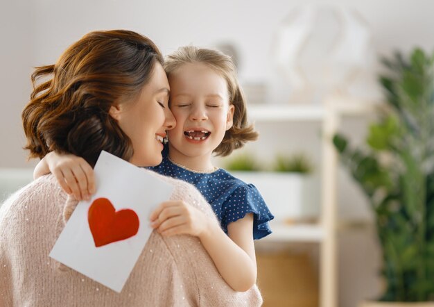 Feliz día de la madre La hija del niño felicita a mamá y le da una postal