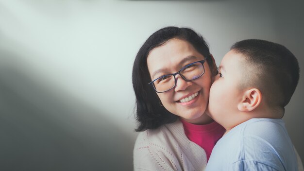 ¡Feliz día de la madre! El hijo del niño felicita a su madre y le besa la mejilla.