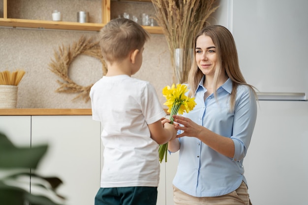 feliz dia de la madre hijo pequeño le da flores a mamá niño felicita a mamá