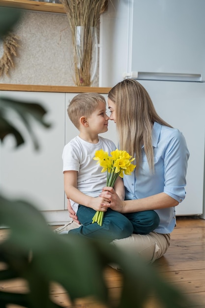 feliz dia de la madre hijo pequeño le da flores a mamá niño felicita a mamá