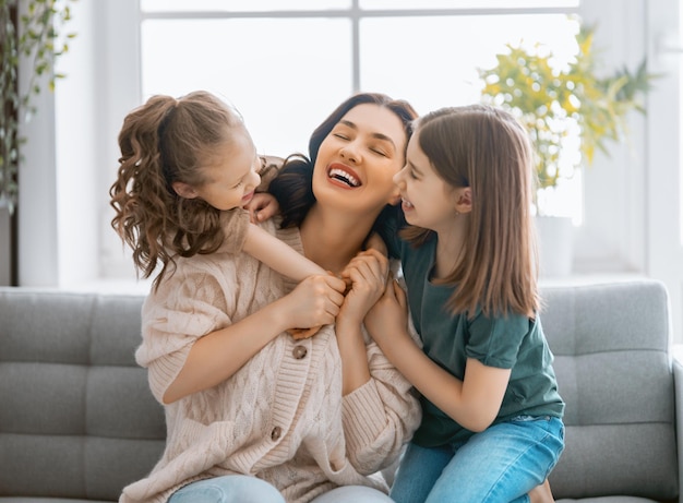 ¡Feliz día de la madre! Mamá y sus hijas niños niñas están jugando, sonriendo y abrazándose. Vacaciones familiares y convivencia.