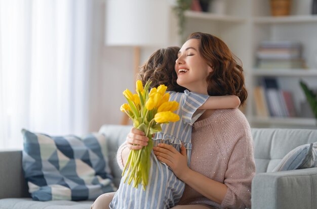 Feliz día de la madre Niño hija felicitando a mamá y dándole flores