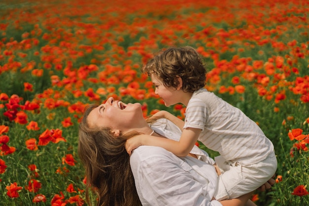 Feliz día de la madre, el niño y la madre están jugando en un hermoso campo de amapolas rojas.