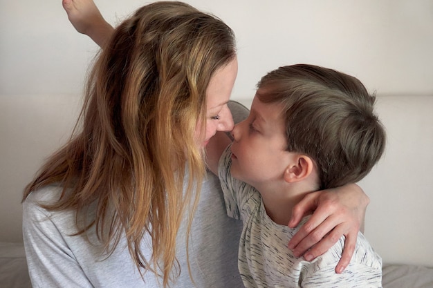 Feliz día de la madre. Niño niño felicita a mamá y le da flores, tulipanes y postal. Mamá e hijo sonriendo y abrazándose. Vacaciones familiares y convivencia. Concepto de saludo del día de la madre.