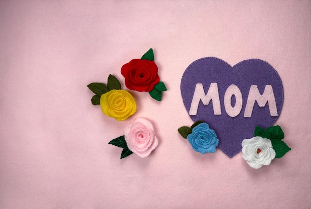 Feliz día de la madre palabras en un tablero de fieltro rosa composición de día de las madres con rosas y un corazón púrpura