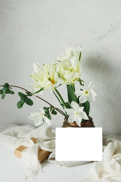 Feliz día de las madres Hermoso ramo en caja de regalo de jarrón vintage y tarjeta vacía en mesa de madera rústica Maqueta de tarjeta de felicitación y elegantes tulipanes blancos de primavera Día de la mujer Espacio para texto