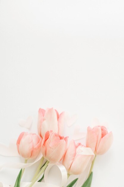 Foto feliz día de la mujer tulipanes rosas con cinta y corazones sobre fondo blanco endecha plana elegante imagen vertical suave maqueta de tarjeta de felicitación con espacio para texto feliz día de la madre día de san valentín