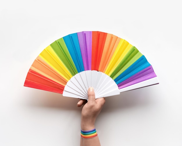 Feliz día del orgullo La mano sostiene el ventilador del arco iris. Cinta con arco iris desi