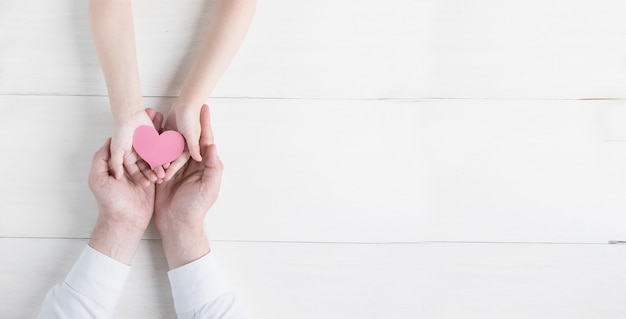 Feliz día del padre Corazón en manos de la hija y el padre sobre un fondo blanco.